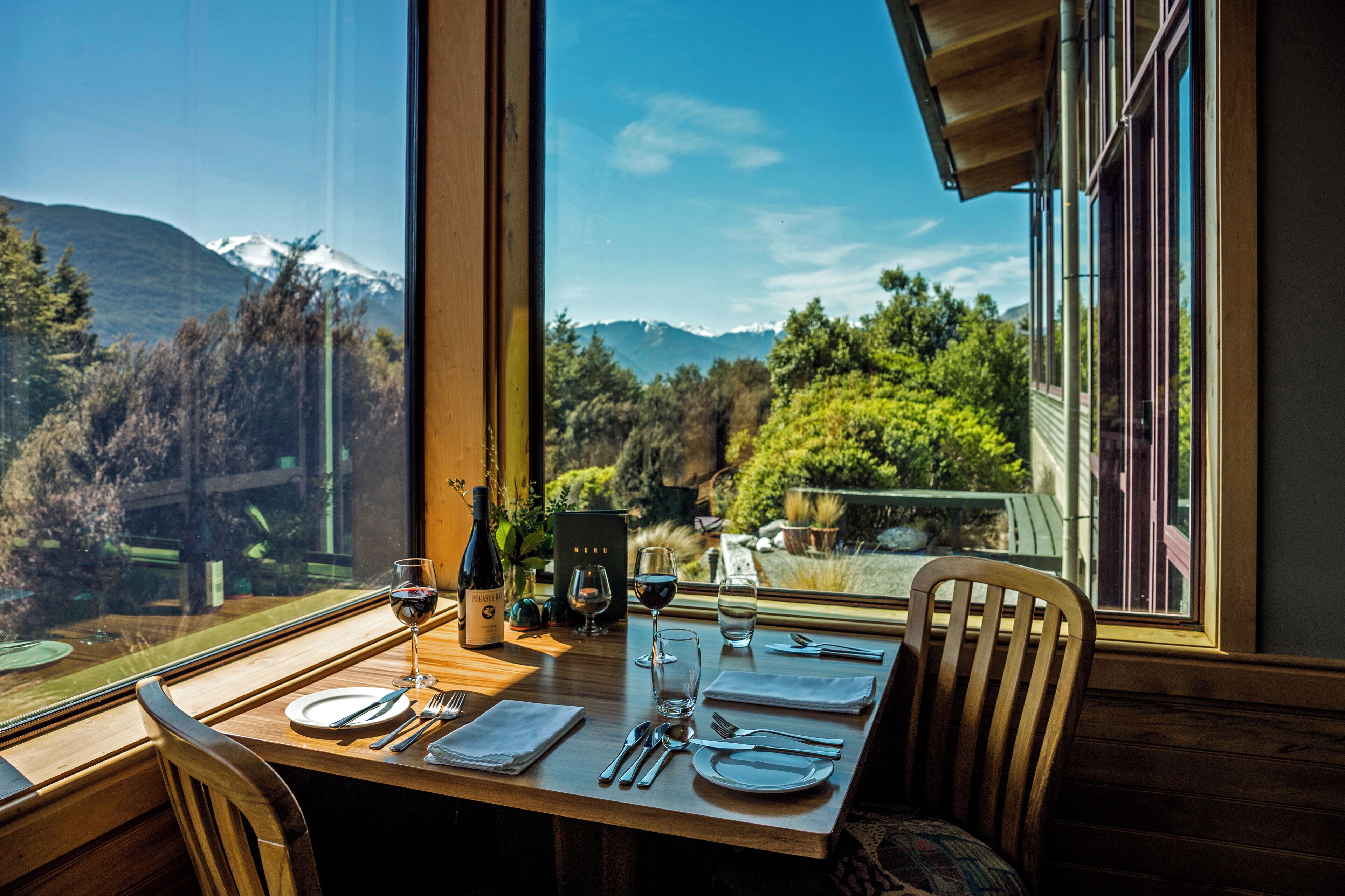 A dining table set for two with a mountain view through large windows.