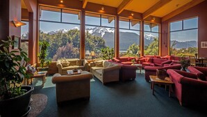 A spacious living room with large windows offering a mountain view, furnished with sofas and a coffee table.