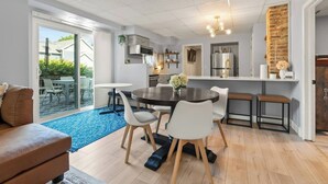 Una cocina moderna con una isla central, una zona de comedor con una mesa redonda y sillas, y una sala de estar con un sofá y una mesita de centro.