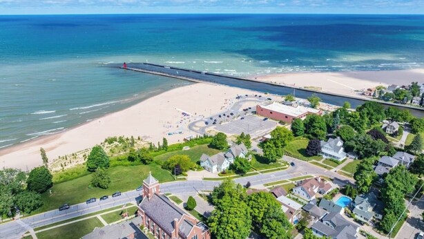 Vista aérea de un pueblo costero con playa, muelle y zonas residenciales.
