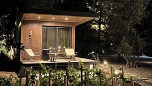 A small, modern cabin with a wooden exterior, a glass door, and a patio area with chairs and a table. - LUN Serena Lodge Chacras de Coria (Chacras de Coria)