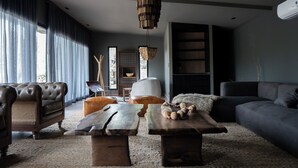 Ein modernes Wohnzimmer mit einer Ledersofa, einem Holztisch und einem großen Fenster mit Vorhängen.