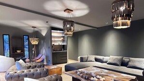 A modern living room with a sectional sofa, leather ottomans, a wooden coffee table, and a hanging light fixture. - LUN Nox Lodge Chacras de Coria (Chacras de Coria)