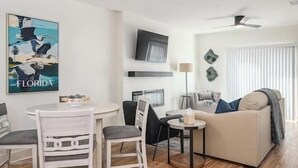Ett modernt vardagsrum med ett runt matbord, två stolar, en soffa och en takfläkt.