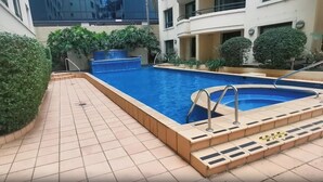 A swimming pool with steps leading into it, surrounded by a tiled patio area. - KozyGuru | Parramatta Studio Steps to Shops, Cafés (Parramatta)