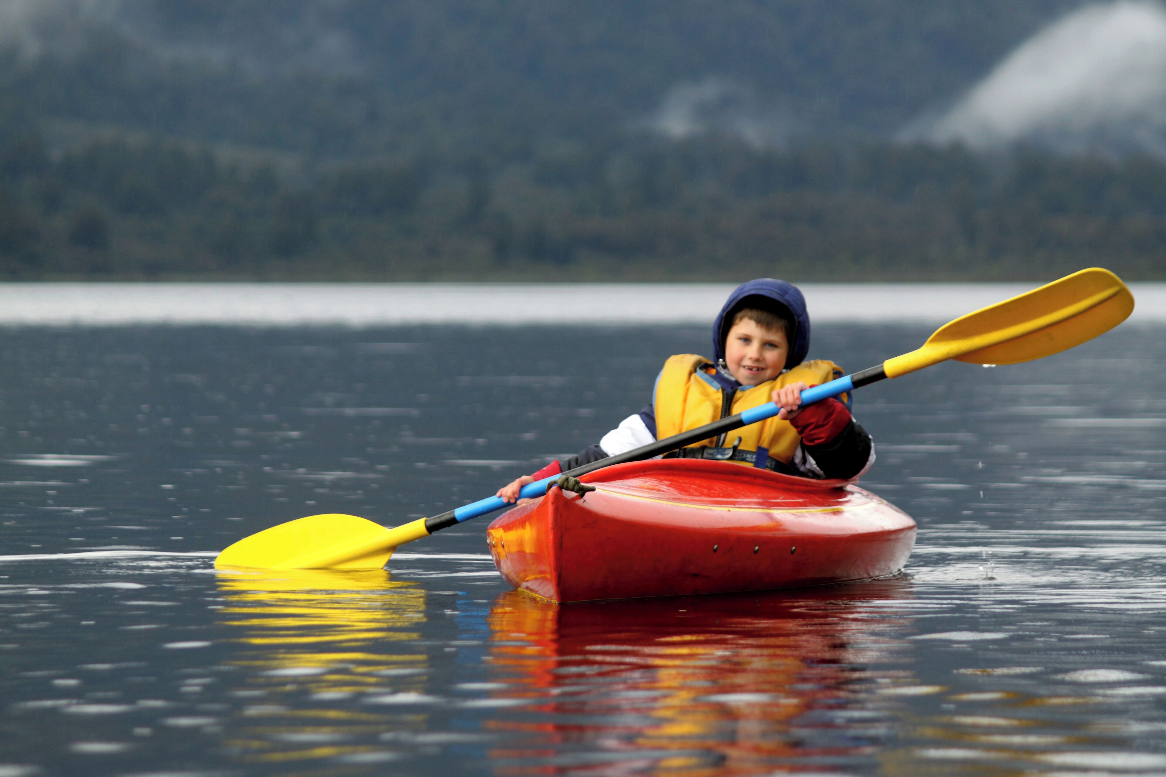 A person in a red kayak on calm water.