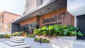 A modern building with a sign reading "Sunset 47" and a well-maintained outdoor area with steps leading to the entrance. - Modern 3BR + Rooftop Pool & Jacuzzi (Cartagena de Indias)