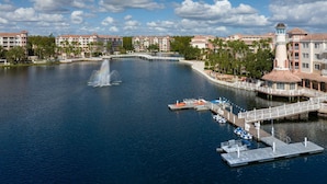 Un hôtel situé au bord de l’eau, avec une fontaine centrale, des bateaux amarrés et un pont qui relie les bâtiments.