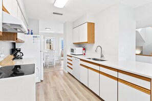 Une cuisine moderne avec des meubles blancs, un plan de travail en bois, un lave-vaisselle encastré et un évier.