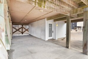 Une pièce vide avec un sol en béton, une porte blanche et une structure de plafond en bois.