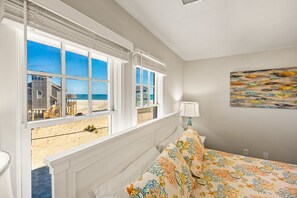 A bedroom with a bed, a window with a view of the beach, and a painting on the wall. - Dolphin: Dog-Friendly Buxton Beach Retreat (Buxton)