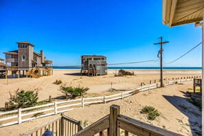 A beachside property with a wooden deck, a small building, and a clear view of the ocean. - Dolphin: Dog-Friendly Buxton Beach Retreat (Buxton)