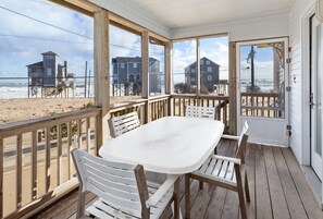 A covered outdoor area with a table and chairs, overlooking a beach with houses in the background. - Dolphin: Dog-Friendly Buxton Beach Retreat (Buxton)