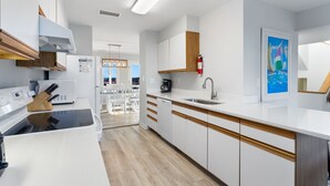 Une cuisine moderne avec des meubles blancs, un plan de travail en bois et une vue sur la salle à manger.