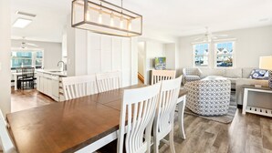 A modern kitchen with white cabinetry, a wooden dining table, and a pendant light.