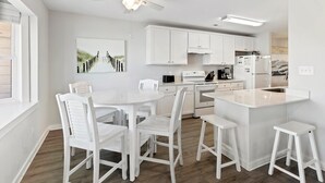 Una cocina moderna con armarios blancos, una isla central con taburetes y un ventilador de techo.