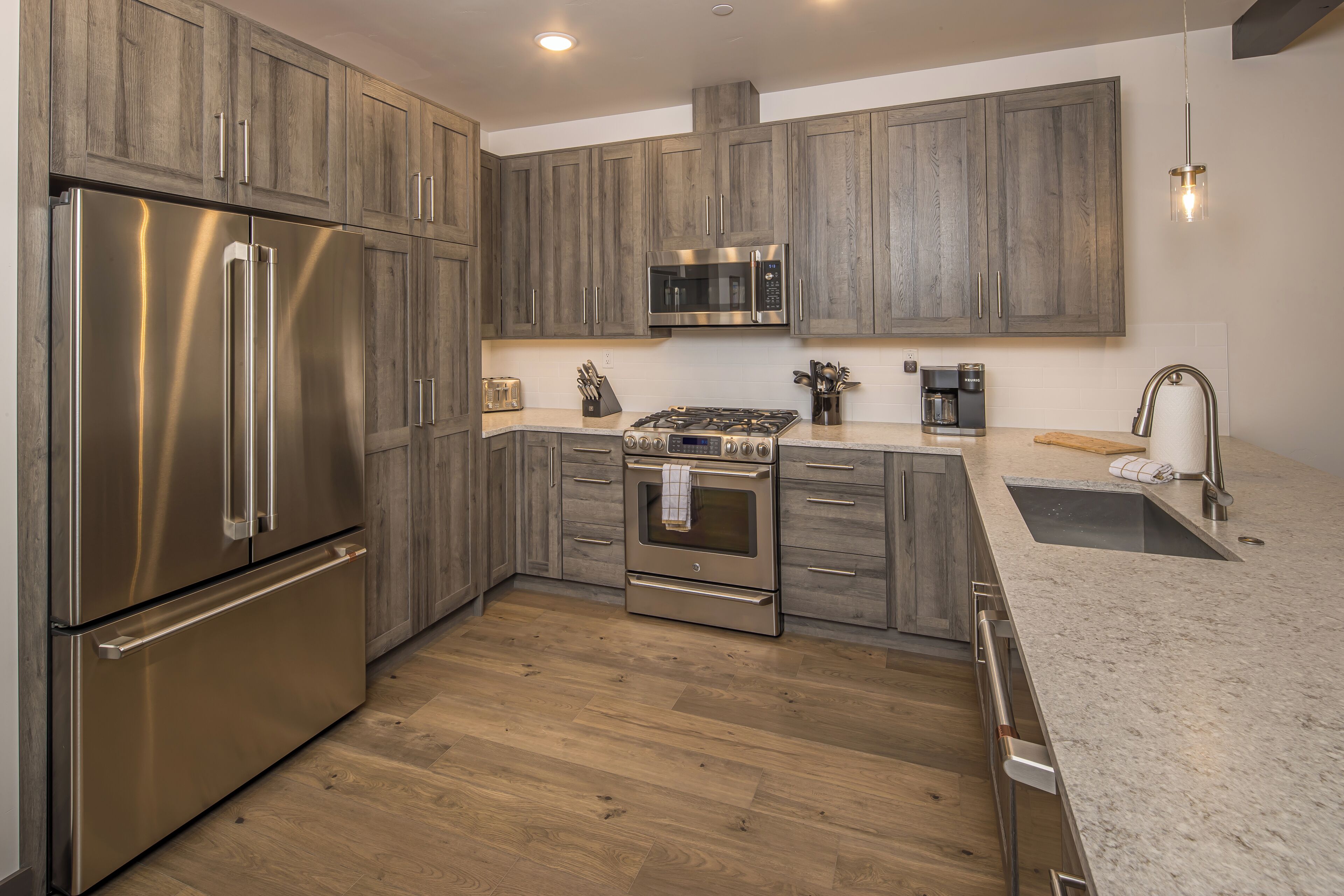 A modern kitchen with wooden cabinets, stainless steel appliances, and a granite countertop.