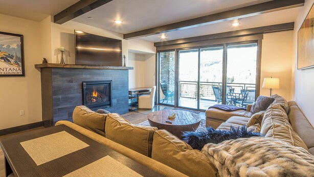 Una sala de estar moderna con chimenea, asientos cómodos y ventanas amplias con vistas.