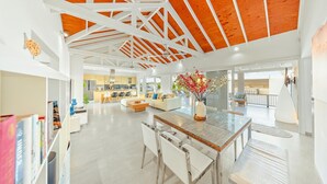 Un salón amplio con techo alto, una isla central con asientos y vistas al exterior.