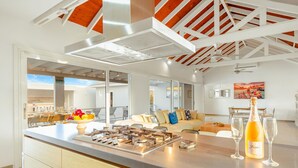 Una cocina moderna con una isla central, una zona de comedor con sofá y un balcón con vistas.