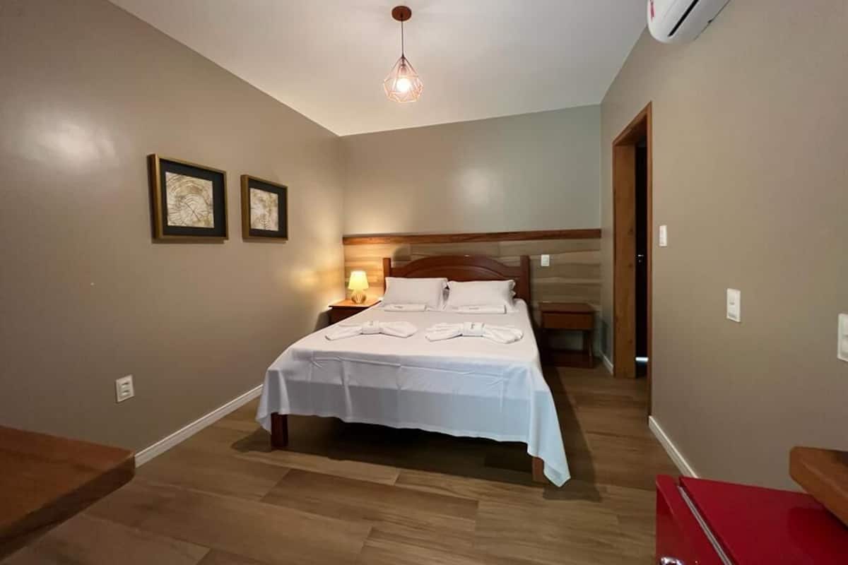 A bedroom with a bed, bedside tables, a lamp, and framed pictures on the wall.