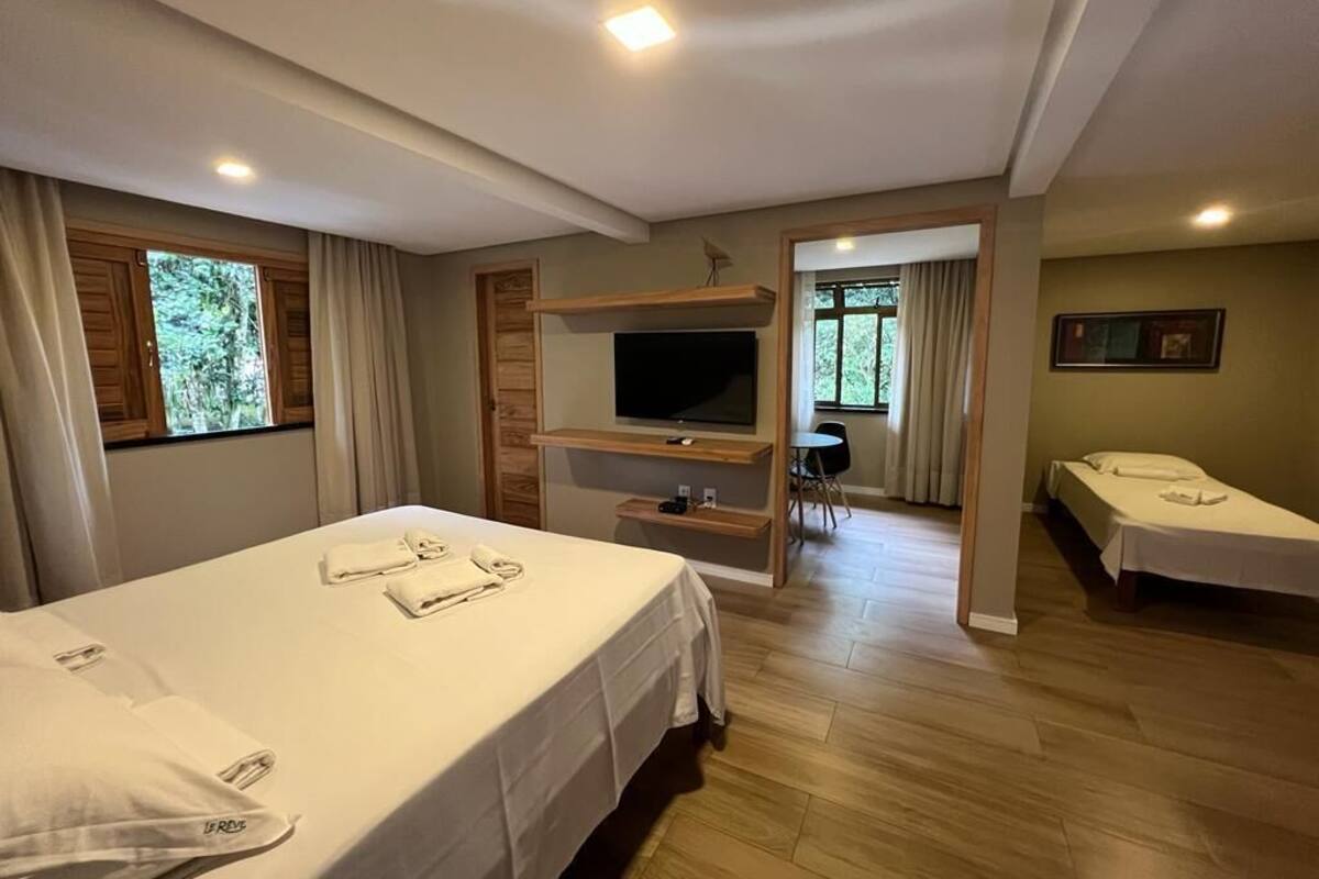 A hotel room with a bed, a TV, a desk, and a chair.