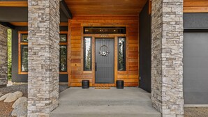 A modern building entrance with a stone facade, a dark wooden door, and a concrete staircase leading up. - Fox & the Fairway- On the golf course in Spring Mtn Ranch w/ AC & club access (McCall)