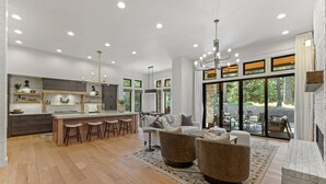 A spacious living area with a kitchen, bar area, and large windows offering a view of the outdoors. - Fox & the Fairway- On the golf course in Spring Mtn Ranch w/ AC & club access (McCall)