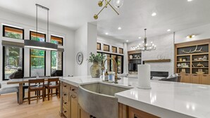 A modern kitchen with a large island, wooden cabinets, and a built-in sink. - Fox & the Fairway- On the golf course in Spring Mtn Ranch w/ AC & club access (McCall)