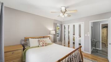 Ein Schlafzimmer mit Bett, Nachttisch, Lampe und Deckenventilator.