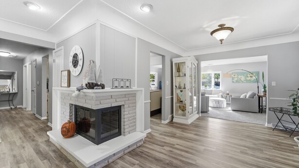 A spacious living room with a fireplace, a dining area, and a kitchen in the background. - Cozy Heights Retreat | Baker's Kitchen & Sleeps 10 (Windsor Heights)