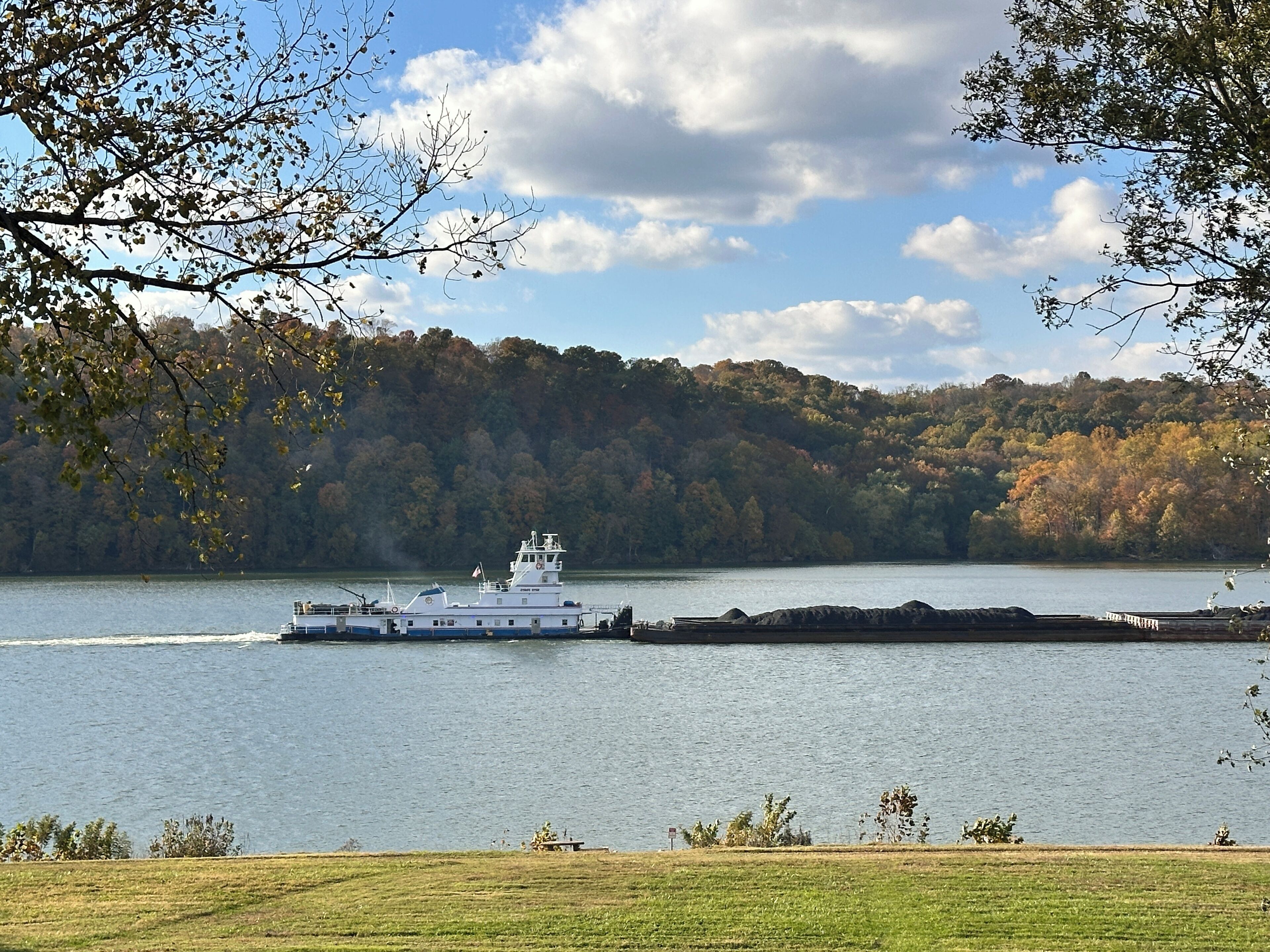 A river with a boat and a forested hillside in the background.