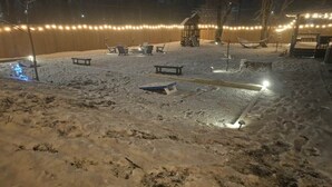 Un espace extérieur enneigé, aménagé avec des sièges et illuminé de guirlandes lumineuses.
