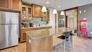 A modern kitchen with wooden cabinets, a stainless steel refrigerator, granite countertops, and pendant lighting. - Spacious 2-Bedroom Urban Oasis (Salt Lake City)