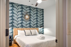 Un lit bien fait, avec du linge de lit blanc, une tête de lit en bois et un élément décoratif mural au-dessus.