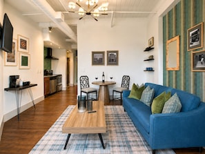 Un salon moderne avec un canapé bleu, une table basse en bois et un coin repas comprenant deux chaises.