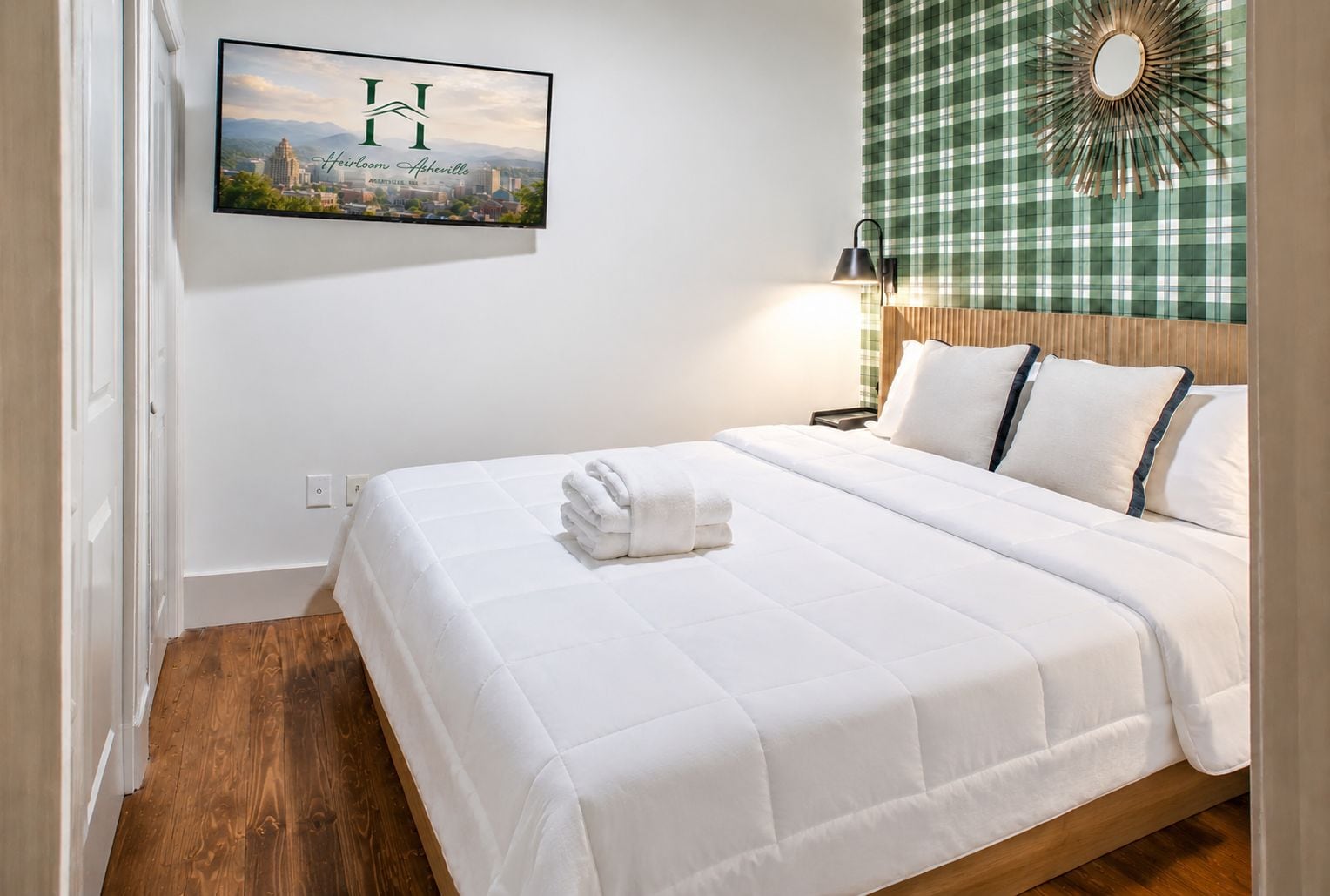 A hotel room with a bed, a wall-mounted picture, and a checkered curtain.