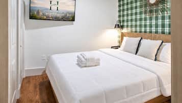 A hotel room with a bed, a wall-mounted picture, and a checkered curtain.