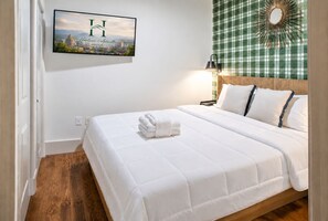 A hotel room with a bed, a wall-mounted picture, and a checkered curtain.
