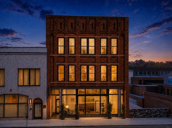 A multi-story brick building with large windows and a ground-level entrance.