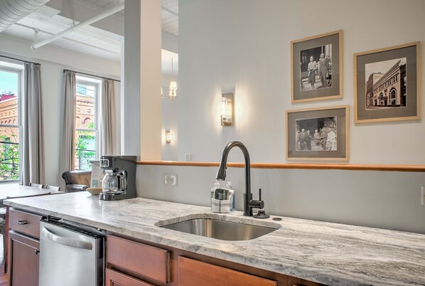A modern kitchen with a stainless steel sink, wooden cabinets, and a marble countertop.