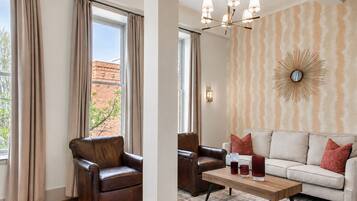 A room with a leather armchair, a sofa, a coffee table, and a patterned wall.