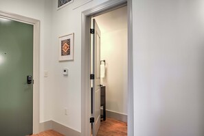 A hallway with a green door, a framed picture on the wall, a light switch, and a thermostat.