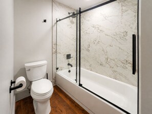 A modern bathroom with a toilet, a shower enclosure, and a bathtub. - The Gatsby at Heirloom Asheville | Downtown Asheville Historic Condo with Two King Suites (Asheville)