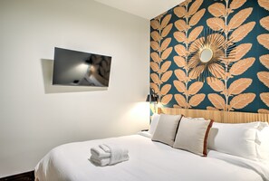 Een hotelkamer met een bed, een wandtelevisie en een decoratief wandpaneel.