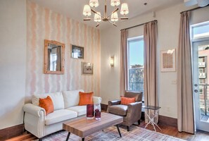 Ein Wohnzimmer mit Sofa, Sessel, Couchtisch und einer Deckenleuchte.