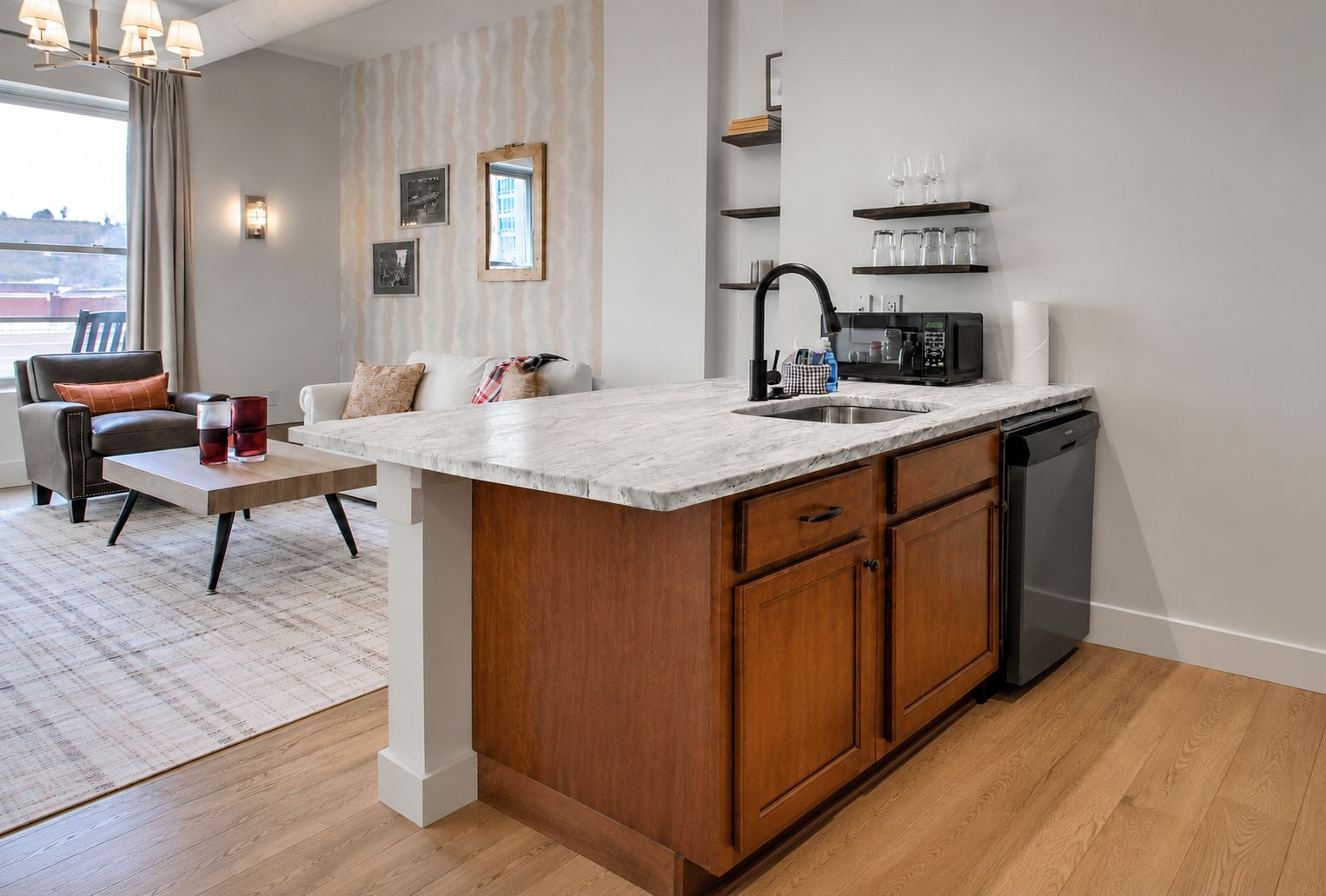 Une cuisine moderne dotée d’un plan de travail en marbre, de meubles en bois, d’un lave-vaisselle encastré et d’un coin repas avec un canapé et une table basse.