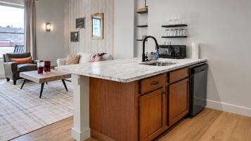 Une cuisine moderne dotée d’un plan de travail en marbre, de meubles en bois, d’un lave-vaisselle encastré et d’un coin repas avec un canapé et une table basse.