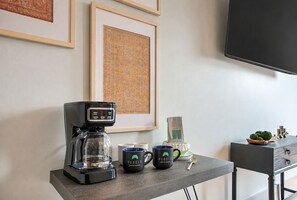 Eine Kaffeemaschine auf einem Tisch, zusammen mit zwei Tassen, einer Flasche und einem Löffel.