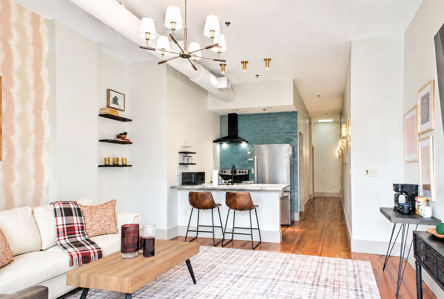 Uma sala de estar moderna com sofá, mesa de centro e área de cozinha com fogão e micro-ondas.